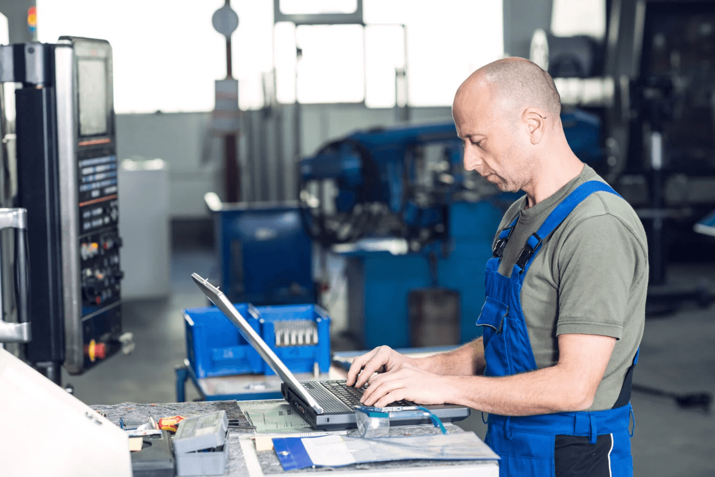 Mann am Laptop in der Fabrik Ein Mann arbeitet mit einem Laptop in einer industriellen Fertigungsumgebung