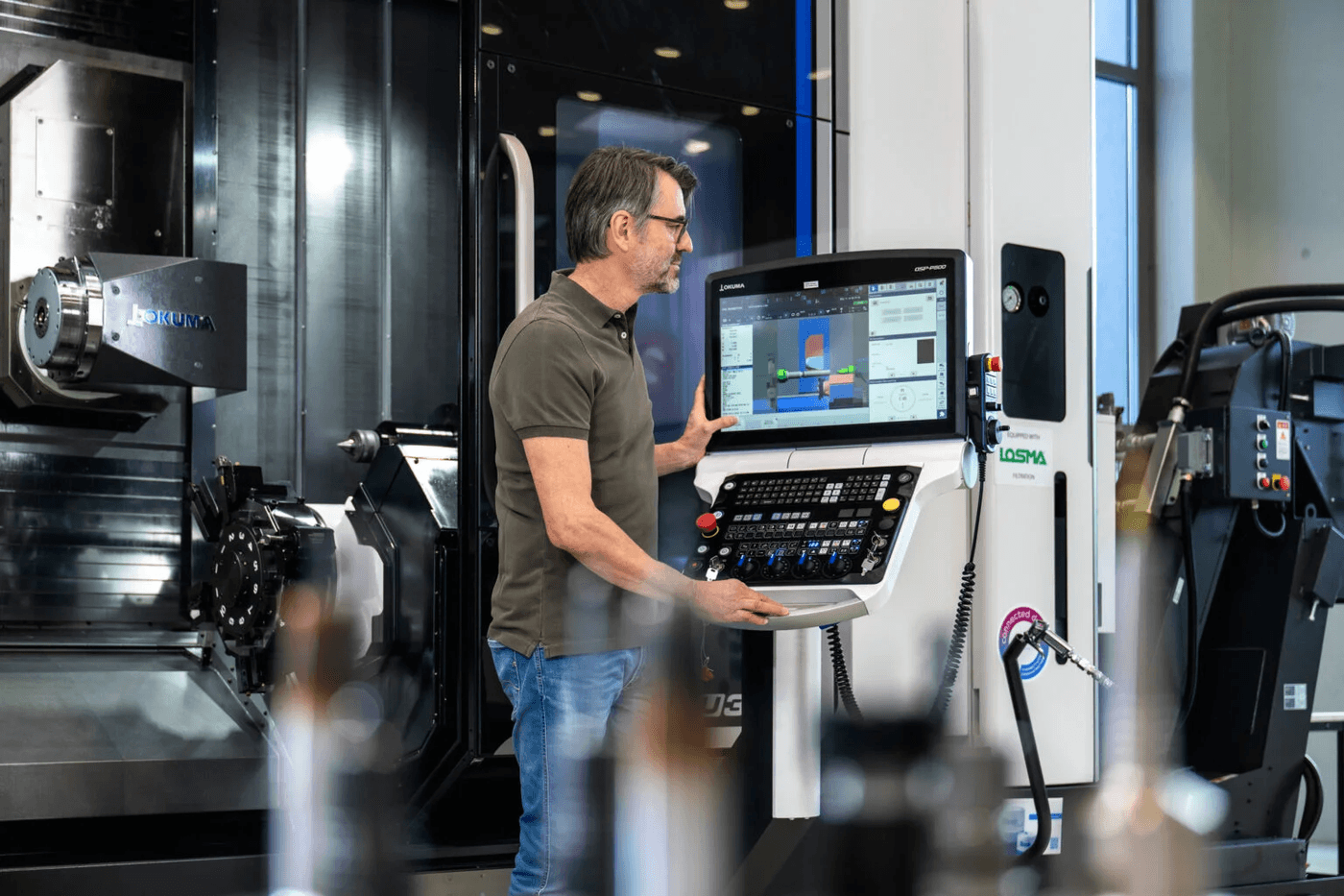 Mann an CNC-Maschine Ein Mann bedient oder überwacht eine CNC-Maschine in der Fertigung